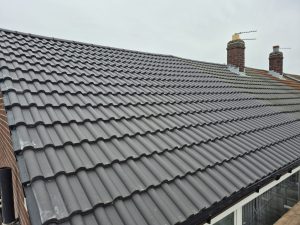 New grey concrete interlocking roof tiles installed on residential property in Leeds with dry verge system