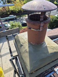 Chimney stack repair with fresh cement flaunching and terracotta pot with bird guard cap in Leeds