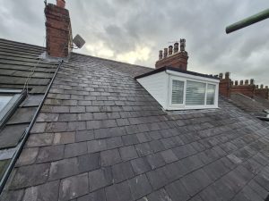 Slate roof with white UPVC dormer window and Velux skylight on Victorian terraced property in Leeds