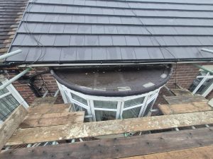 Bay window flat roof repair with felt covering and slate tile roof on Leeds brick property with scaffolding